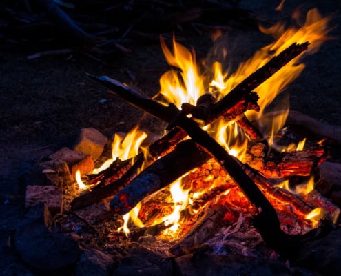 Wood in a shape of a cross is burned with multiple pieces of wood.