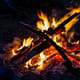 Wood in a shape of a cross is burned with multiple pieces of wood.
