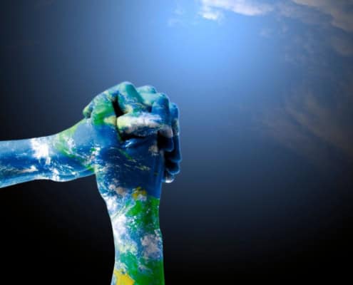 Hands painted like Earth clasped together in prayer, symbolizing global solidarity and environmental care