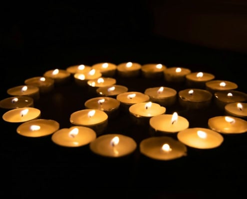 white candles on black surface in shape of peace symbol promoting a nonviolent approach