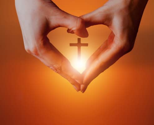 Hands in the shape of a heart with a cross in the middle